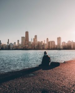 Man sitting on edge of Lake Michigan staring at Chicago Skyline